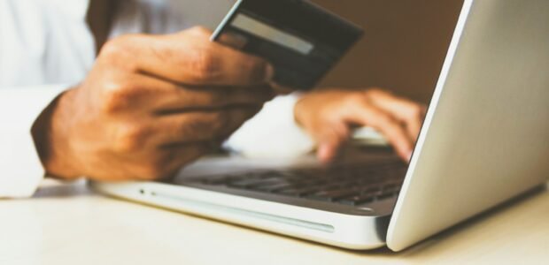 Person holding a card while using a laptop to shop online, relevant to Cyber Monday deals